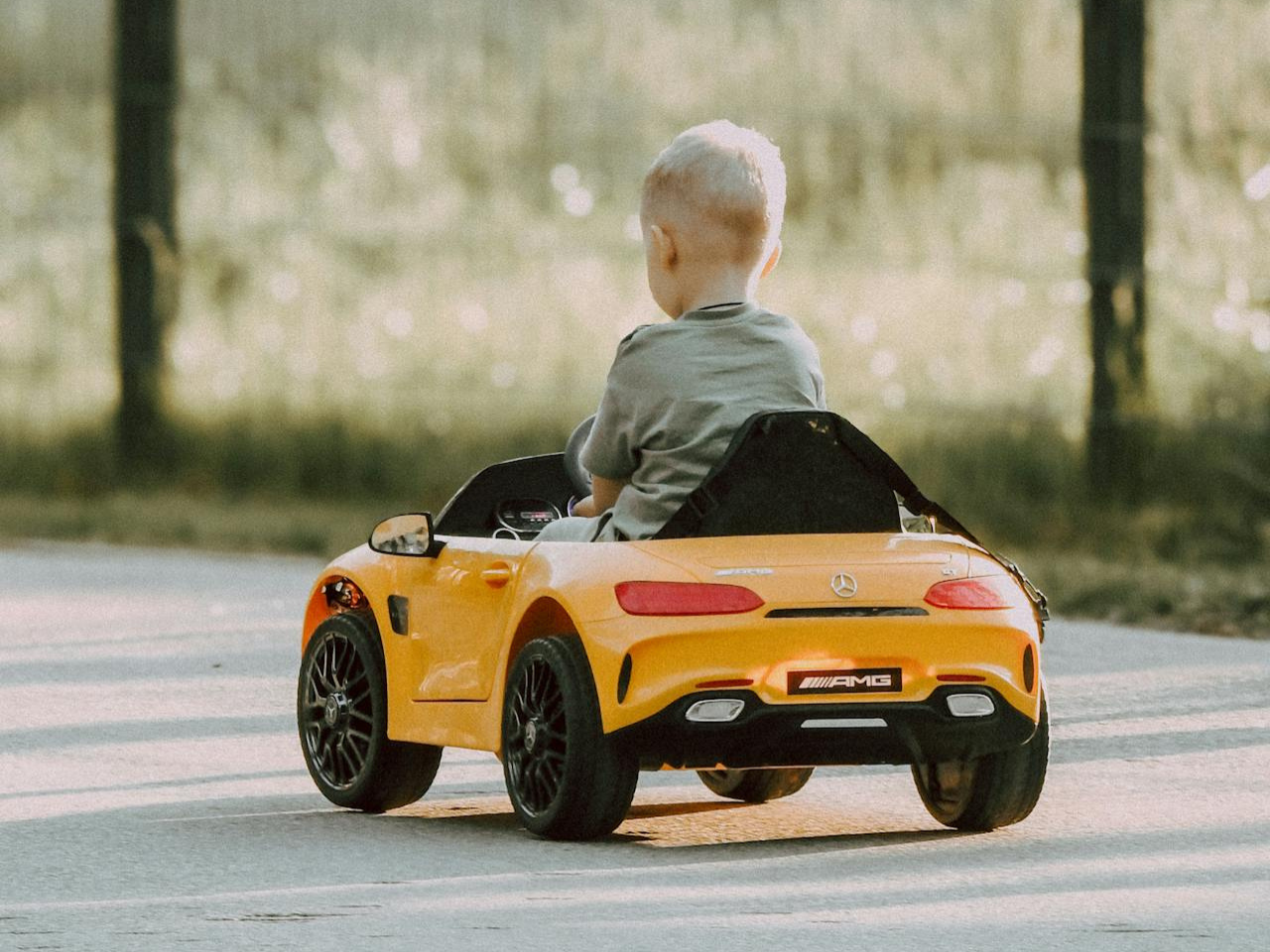 Can you test drive a car without a license? No! Image of a toddler driving a yellow play car