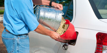 Main pouring cash into a cars fuel tank