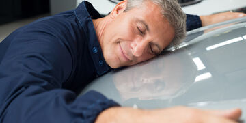 Man fulfilling his dream of buying a new car and giving it a big hug