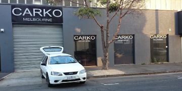 White car with boot open in front of Carko dealership