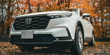 A photo of a Honda SUV parked in a forest in autumn.